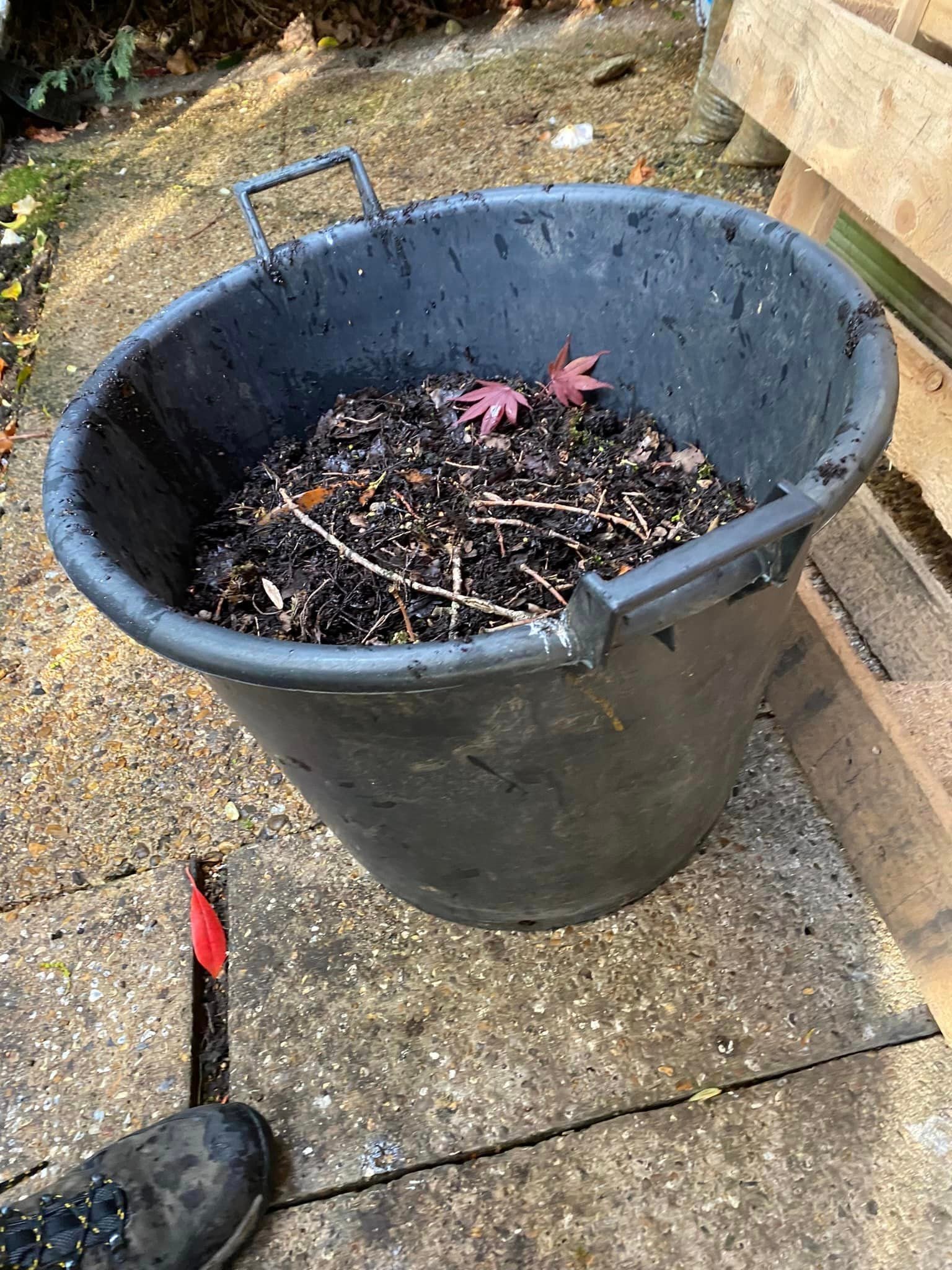 About Us 5 An image of a pail full of dirt and branches from gutters